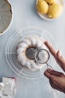 Hände einer Frau bestreuen Puderzucker auf einem Ringkuchen - IPF000302