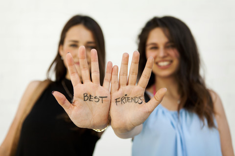 Two young women showing their palms with writing 'best friends' stock photo