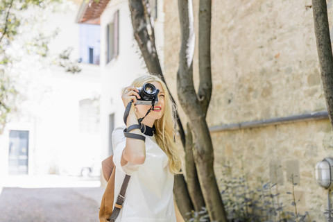 Blonde Frau beim Fotografieren mit Kamera, lizenzfreies Stockfoto