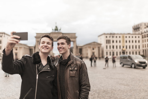 Zwei Jugendliche machen ein Smartphone-Bild von sich vor dem Brandenburger Tor in Berlin, lizenzfreies Stockfoto