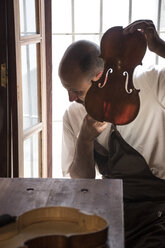 Luthier tuning the top plate of a violin in his workshop - ABZF000777