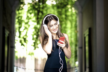 Junge Frau mit Kopfhörern und Smartphone - SIPF000590