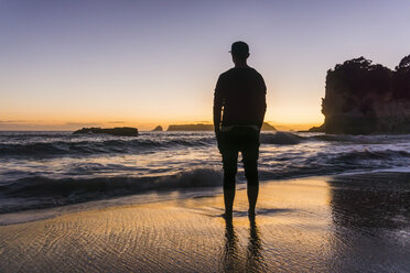 Neuseeland, Wanganui, Silhouette eines Mannes, der am Strand steht und auf das Meer schaut - UUF007937