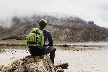 New Zealand, Tongariro National Park, back view of hiker with backpack looking to Tongariro Mountain - UUF007947