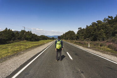 Neuseeland, Tongariro National Park, Rückenansicht eines Wanderers mit Rucksack auf der Landstraße - UUF007952