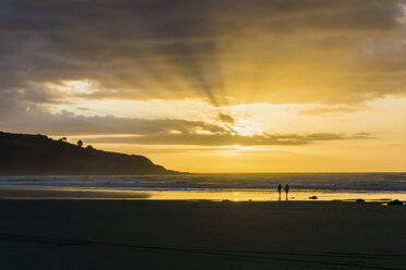 Silhouette von zwei Menschen am Strand bei Gegenlicht - UUF007956