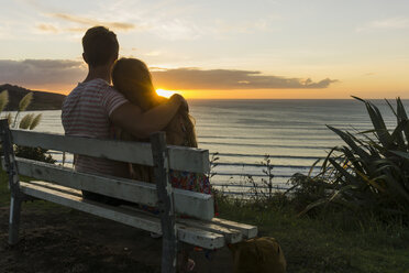 Couple in love sitting on bench looking at sunset - UUF007965