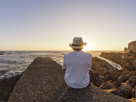 Portugal, älterer Mann sitzt auf einer Mauer am Hafen bei Sonnenuntergang - LAF001663
