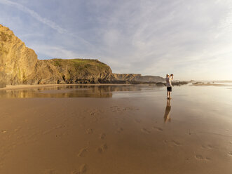 Portugal, Senior man standing at beach taking picture with digital tablet - LAF001671