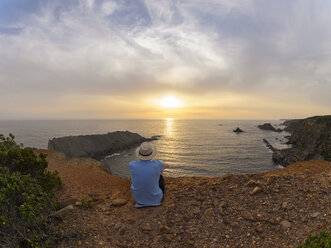 Portugal, älterer Mann sitzt in der Bucht und beobachtet den Sonnenuntergang - LAF001678