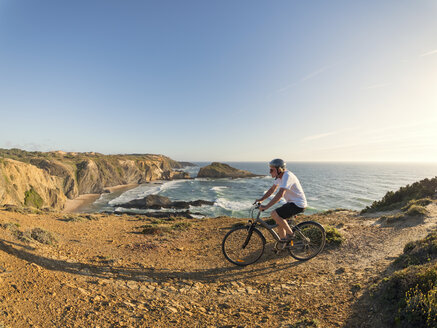 Portugal, Älterer Mann beim Mountainbiking am Meer - LAF001680