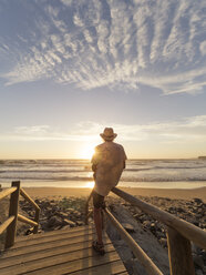 Portugal, älterer Mann sitzt auf dem Geländer am Strand - LAF001686