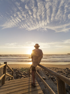 Portugal, älterer Mann sitzt auf dem Geländer am Strand - LAF001686
