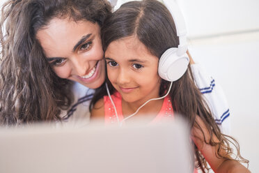 Glückliches Teenager-Mädchen und ihre kleine Schwester mit Laptop und Kopfhörern - SIPF000618