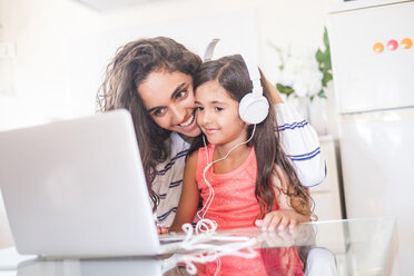 Glückliches Teenager-Mädchen und ihre kleine Schwester mit Laptop und Kopfhörern - SIPF000619