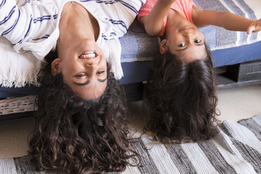 Porträt eines lächelnden Teenager-Mädchens und ihrer kleinen Schwester auf dem Bett liegend - SIPF000625