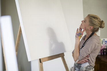 Eine Frau betrachtet die Leinwand, bevor sie ihr Kunstwerk im Heimstudio aufstellt - ZEF008879