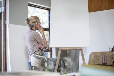 Eine Frau betrachtet die Leinwand, bevor sie ihr Kunstwerk im Heimstudio aufstellt - ZEF008880