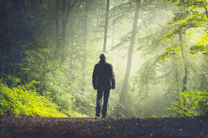 Man walking on forest track in morning light - DWIF000757