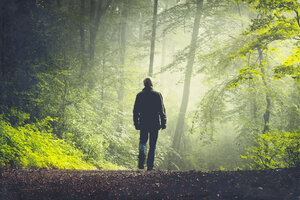 Mann geht auf Waldweg im Morgenlicht - DWIF000757
