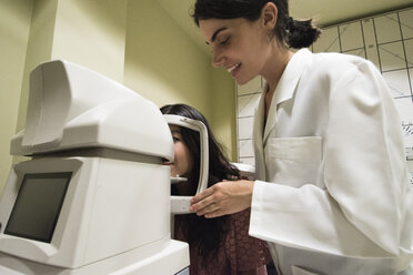 Ophthalmologist placing the head of a patient in an ophtalmological machine to examine eyesight of a patient in an ophthalmic clinic - ABZF000797