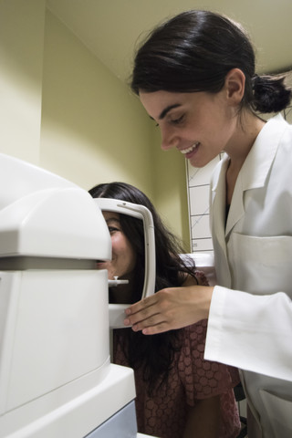 Ophthalmologist placing the head of a patient in an ophtalmological machine to examine eyesight of a patient in an ophthalmic clinic stock photo