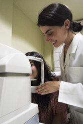 Ophthalmologist placing the head of a patient in an ophtalmological machine to examine eyesight of a patient in an ophthalmic clinic - ABZF000798