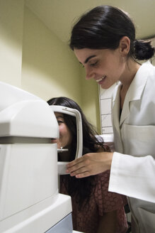 Augenarzt, der den Kopf eines Patienten in eine ophthalmologische Maschine setzt, um die Sehkraft eines Patienten in einer Augenklinik zu untersuchen - ABZF000798