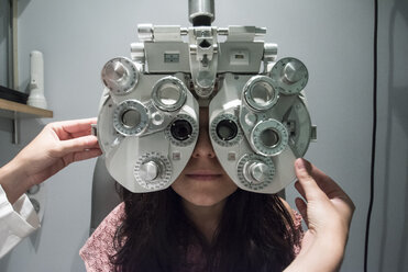 Ophthalmologist adjusting an optometrist phoropter, ready for eye calibration of a patient - ABZF000803