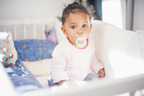 Porträt eines müden kleinen Mädchens mit Schnuller im Kinderbett - YNF000021