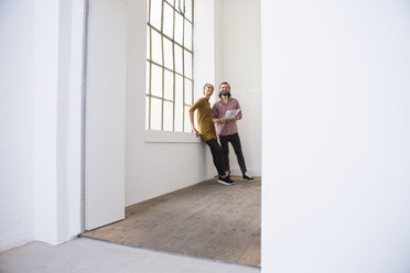 Young couple in new home looking around - RBF004594