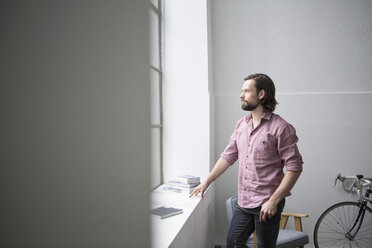 Man standing at the window, looking at distance - RBF004621