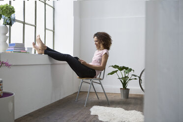 Woman sitting in chair using digital tablet - RBF004655