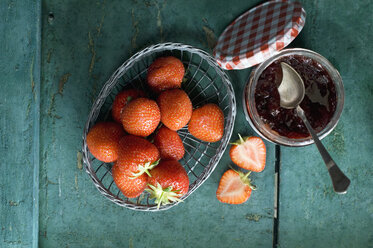 Glass of strawberry jam and strawberries in a wire basket - ASF005938