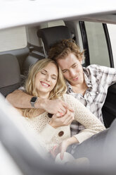 Junges verliebtes Paar sitzt im Auto und hält sich die Hände - PESF000183