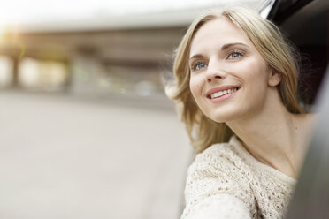 Portrait of smiling young woman leaning out of car window watching something - PESF000186