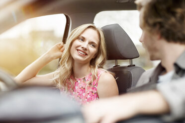 Portrait of smiling blond woman sitting on passenger seat in a car talking to her friend - PESF000190