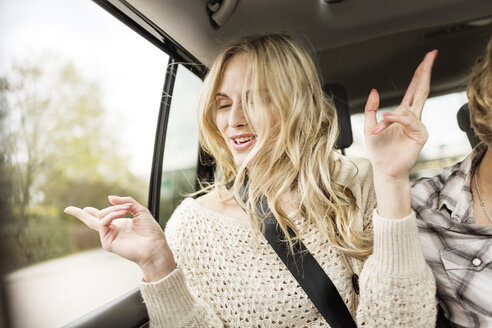 Porträt einer jungen Frau mit geschlossenen Augen, die in einem Auto Musik hört - PESF000193