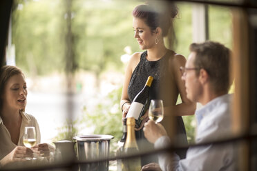 Kellnerin zeigt Weinflasche an Kunden in Restaurant - ZEF008897