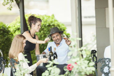 Kellnerin und Kunden in einem Restaurant, die Wein in Gläsern prüfen - ZEF008904