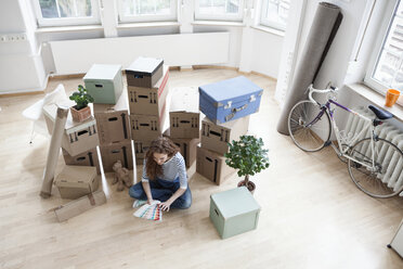 Woman surrounded by cardboard boxes with color samples on floor - RBF004676