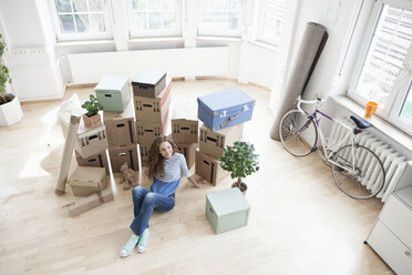 Woman surrounded by cardboard boxes sitting on floor - RBF004677