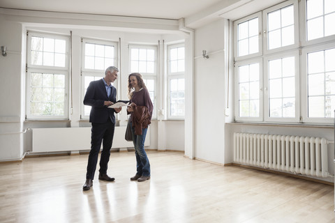 Immobilienmakler im Gespräch mit einem Kunden in einer leeren Wohnung, lizenzfreies Stockfoto