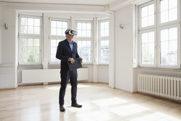 Immobilienmakler mit Virtual-Reality-Brille in leerer Wohnung - RBF004686