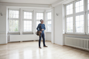 Man looking around in empty apartment - RBF004687