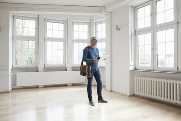 Mann sieht sich in einer leeren Wohnung um - RBF004688