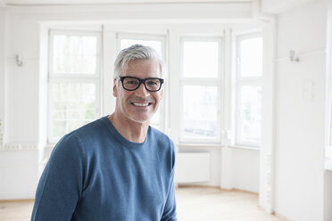 Portrait of smiling man in empty apartment - RBF004696