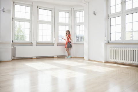 Frau sieht sich in einer leeren Wohnung um, lizenzfreies Stockfoto