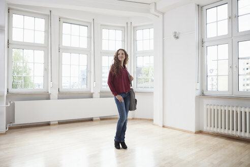 Frau sieht sich in einer leeren Wohnung um - RBF004713