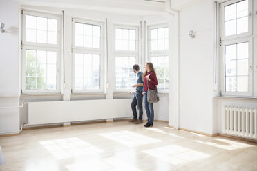 Couple looking around in empty apartment - RBF004717